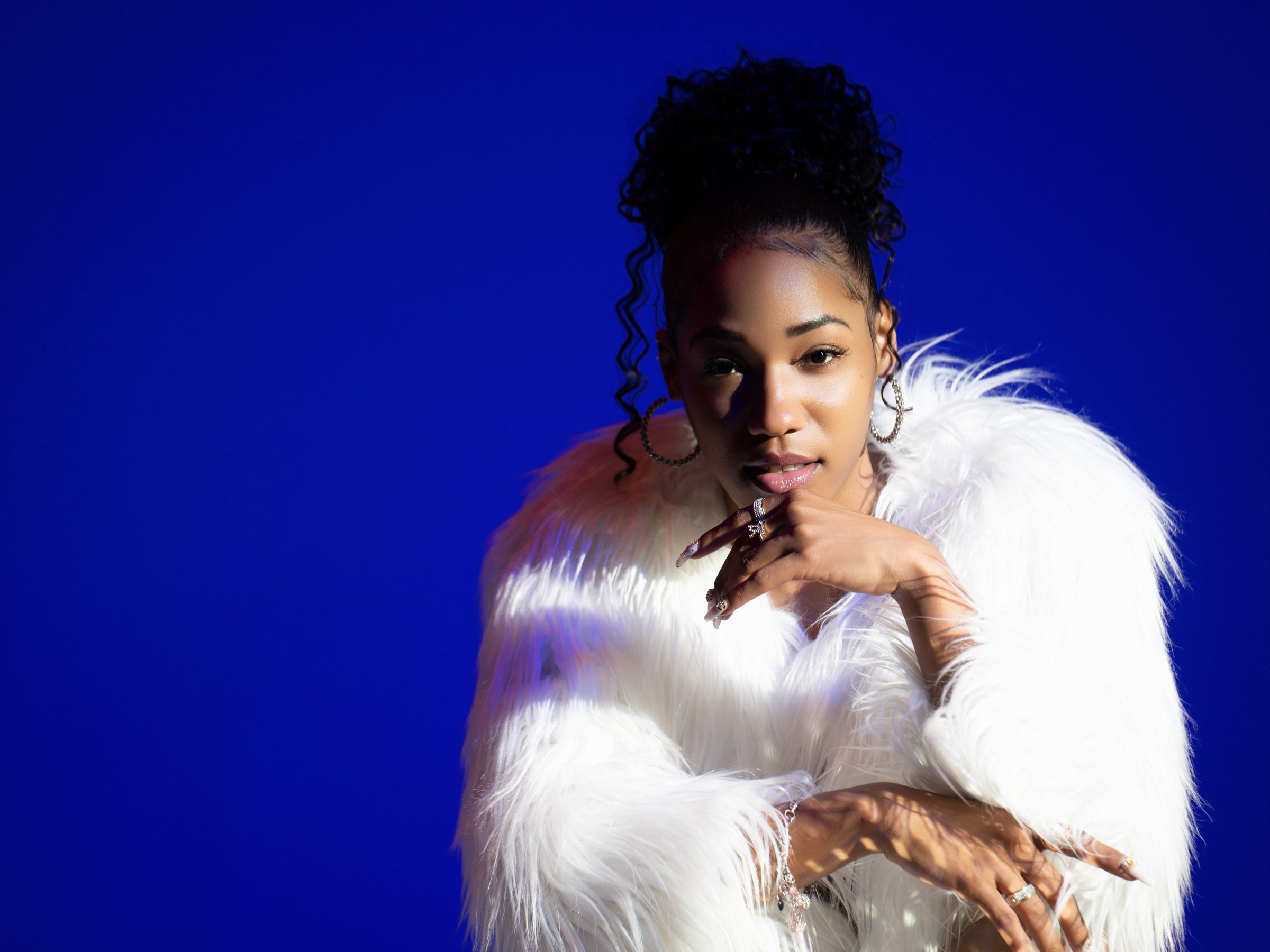 Lexxi Meshan in white fur against a royal blue backdrop